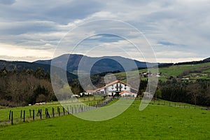 Typical Basque farmhouse with sheep grazing on a cloudy day