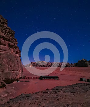 Typical Bedouin tents camp with mountains in background and starry sky at night