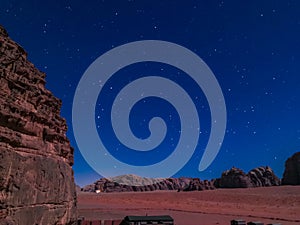 Typical Bedouin tents camp with mountains in background and starry sky at night