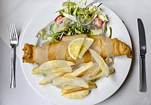 Typical british fish and chips: Haddock, fries and salad on white plate