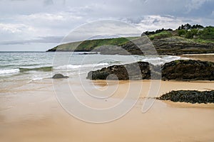 Typical brittany landscape with lonely beach with rocks covered with algae and seaweed and cloudy sky in the background