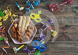 Typical carnival desserts with carnival decorations on a wooden background