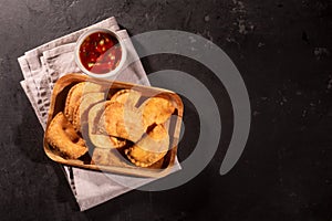 Typical Colombian empanadas served with spicy sauce on black background