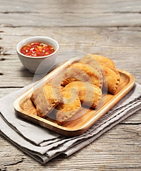 Typical Colombian empanadas with spicy sauce on wooden surface