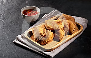 Typical Colombian empanadas usually served with spicy sauce on black background