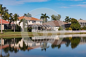 Typical concrete house on the shore of a lake in southwest Florida in the countryside with palm trees, tropical plants and flowers