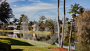 Typical concrete house on the shore of a lake in southwest Florida in the countryside with palm trees, tropical plants and flowers