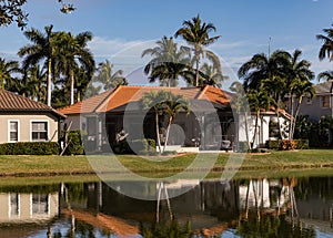 Typical concrete house on the shore of a lake in southwest Florida in the countryside with palm trees, tropical plants and flowers