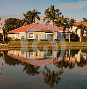 Typical concrete house on the shore of a lake in southwest Florida in the countryside with palm trees, tropical plants and flowers