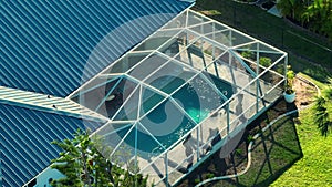 Typical contemporary American big swimming pool on backyard of private house with outside lanai enclosure covering