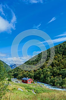 Typical countryside Norwegian landscape with red painted wall house. Cloudy summer morning in Norway, Europe.