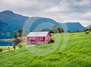 Typical countryside Norwegian landscape with red painted wall house. Cloudy summer morning in Norway, Europe. Beauty of nature