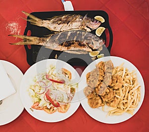 Typical dominican food during lunch on the beach: grilled fish with salad, fries and tostones fried platain photo