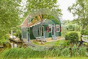 Typical Dutch green wooden house with water channel and garden