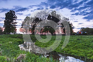 Typical Dutch landscape. small water stream across a green meadow and a small house