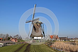 Typical Dutch polder landscape with an old mill with thatched cover.