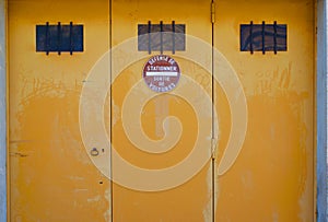 vintage car garage in france with no parking sign (defense de stationner). weathered yellow car garage door. photo