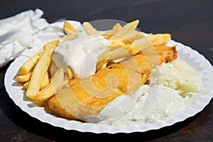 Typical German Friesland deep fried Pollack fish in beer batter with French fries, mayonnaise, sauce tartar and coleslaw on wooden