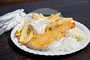 Typical German Friesland deep fried Pollack fish in beer batter with French fries, mayonnaise, sauce tartar and coleslaw on wooden