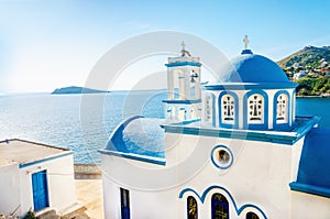 Typical Greek blue dome of white church with sea view in sunny d