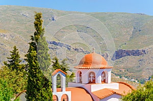 Typical Greek church in mountains with cyprus in the garden, Greece