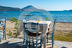 Typical Greek seaside tavern table with wooden chairs by the sea coast in Gialova near Pylos city, Messinia, Greece
