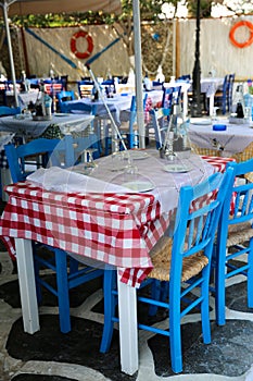 Typical Greek tavern with blue chairs and tables with chequered