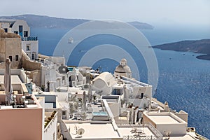 Typical Greek village with church tower lying far over the ocean with cruise ship approaching, Fira, Santorini, Greece