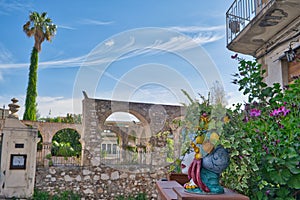 typical head of the moors as a flower vase and old stone walls in the background in taormina, sicily