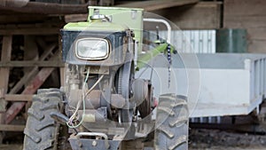 Typical heavy diesel walking tractor with trailer. Agricultural transport equipment of the countryside. Portable