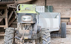 Typical heavy diesel walking tractor with trailer. Agricultural transport equipment of the countryside. Portable agricultural
