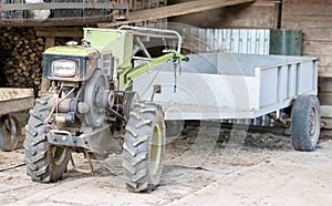 Typical heavy diesel walking tractor with trailer. Agricultural transport equipment of the countryside. Portable agricultural