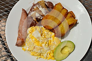 Typical Honduran breakfast of scrambled eggs, fried plantain, avocado, refried beans, tortilla chips and ham