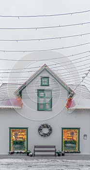 Typical icelandic white wooden house with snowy roof in Selfoss on a foggy cloudy day with Christmas lighting on the windows full