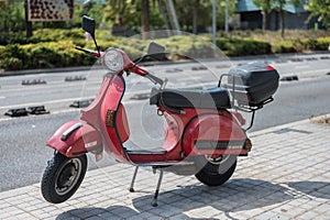 Typical Italian city motorcycle, the red Vespa P 200 E in the city