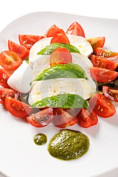 Typical Italian dish from the Campania area mozzarella, tomatoes and pesto of basil,  called caprese on white background