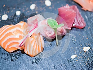 Typical Japanese dish of sushimi with tuna salmon roll on a black background