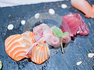 Typical Japanese dish of sushimi with tuna salmon roll on a black background