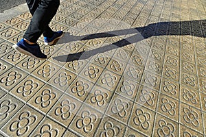 Typical La Flor modernist symbol tiles at Barcelona walkway with person step and shadow Barcelona Spain