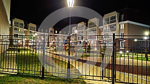 Typical modern cityscape in a new neighborhood with a playground in dark night with lanterns