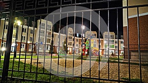 Typical modern cityscape in a new neighborhood with a playground in dark night with lanterns