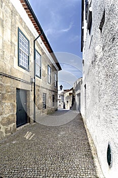 Typical narrow alley paved with cobblestones and with old stone houses in the center of the old town of Guimaraes