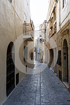Typical narrow street with an ancient stone buildings in Mdina