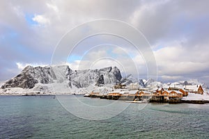 Typical Norwegian landscape. Beautiful view of scenic Lofoten Islands winter scenery with traditional yellow fisherman Rorbuer cab