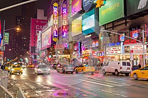 Typical NYC Manhattan Avenue Near Times Square at Night. Vehicles Moving on the Road, Broadway Theaters, Billboards, LED Screens