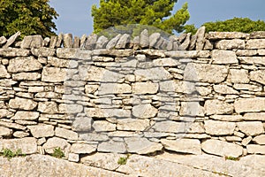 Typical old French dry wall built with stacked stones not fixed with mortar but simply overlapped and interlocked - France -