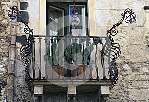 Typical old residential house with balcony decorated by cacti in flower pots. Authentic decoration of balconies in Taormina.