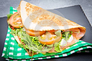 Typical piadina romagnola with ham, cheese and rocket photo