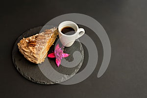 A typical Portuguese cake made of cookies called Bolo de Bolasa with cream, pecans, black and white chocolate on a black slate