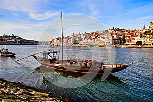 Typical portuguese wooden boats, called  `barcos rabelos `transporting wine barrels on the river Douro with view on Villa Nova de